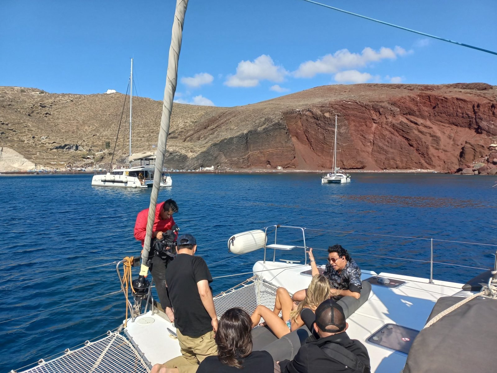 The crew filming the presenters on the catamaran's bow, anchored off Red Beach, Santorini, October 2022